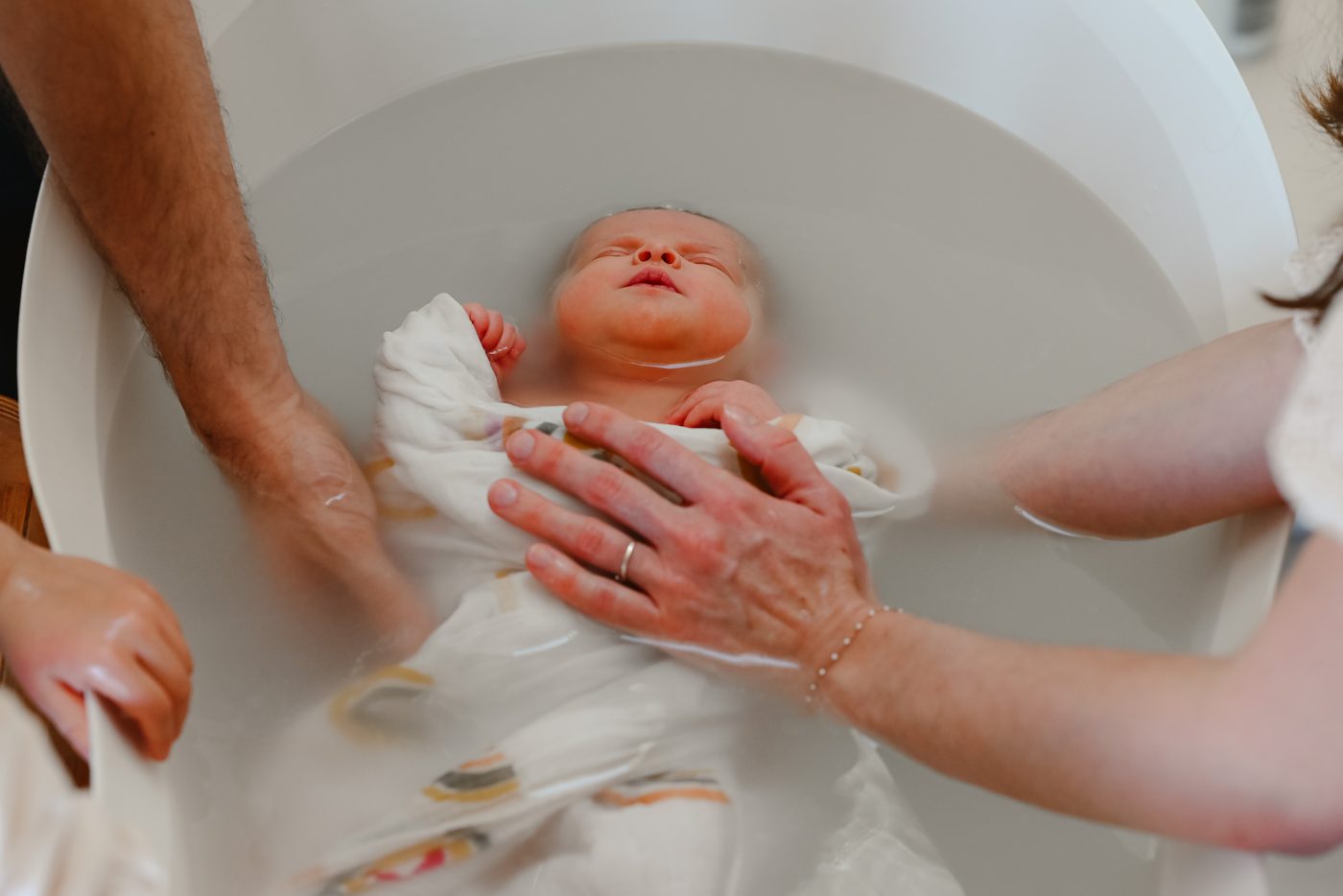 Bébé porté doucement pendant le bain enveloppé